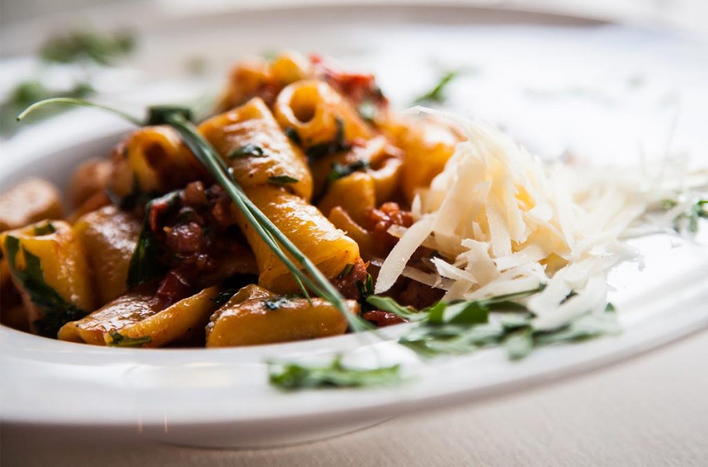 Close up of sausage, pasta, and cheese with garnishes.